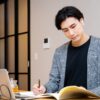 オンライン英会話のレッスンを受けながら自宅で勉強する男性