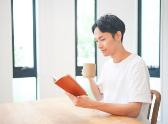 自宅で飲み物を片手に勉強する男性