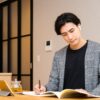 タブレットを見ながらノートを取る男性