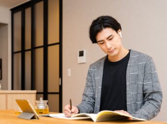タブレットを見ながらノートを取る男性