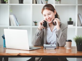 ヘッドホンを外しながら笑顔でノートパソコンを見る女性