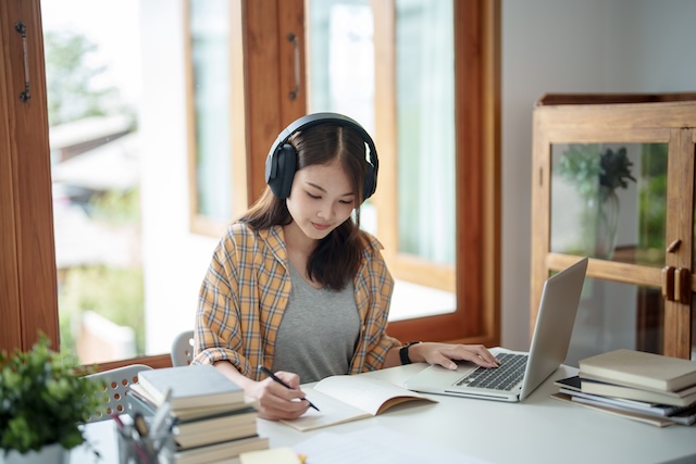 自宅でヘッドホンを付けて勉強する女性