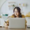 ノートパソコンの前で勉強するメガネをかけた女性
