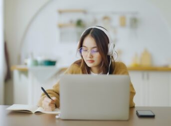 ノートパソコンの前で勉強するメガネをかけた女性