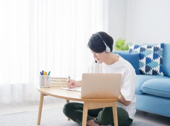 自宅でオンライン英会話レッスンを受ける私服の若い男性