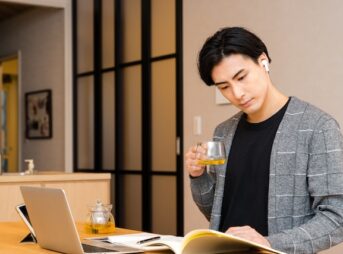 自宅でお茶を片手に勉強する若い男性