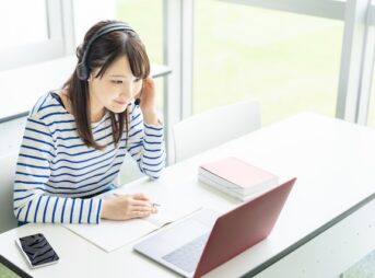 教室でオンライン英会話のレッスンを受ける私服の若い女性