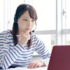 教室でオンライン英会話レッスンを受けながら考える若い女性