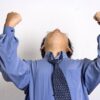 両手でガッツポーズをしているスーツの男性