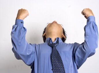 両手でガッツポーズをしているスーツの男性