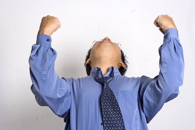 両手でガッツポーズをしているスーツの男性