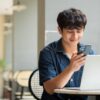 カフェでスマートフォンを見ながら喜ぶ男性