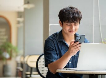 カフェでスマートフォンを見ながら喜ぶ男性