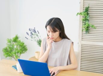 ノートパソコンを見ている緊張している様子の若い日本人女性