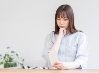 スマートフォンを見て不安そうな若い女性