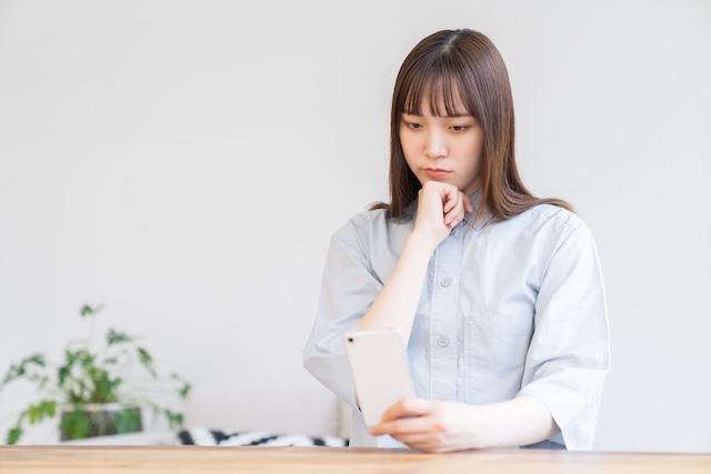 スマートフォンを見て不安そうな若い女性